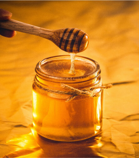 A jar of golden honey with a honey dipper, emphasizing the natural preservation qualities of honey that prevent it from spoiling over time.